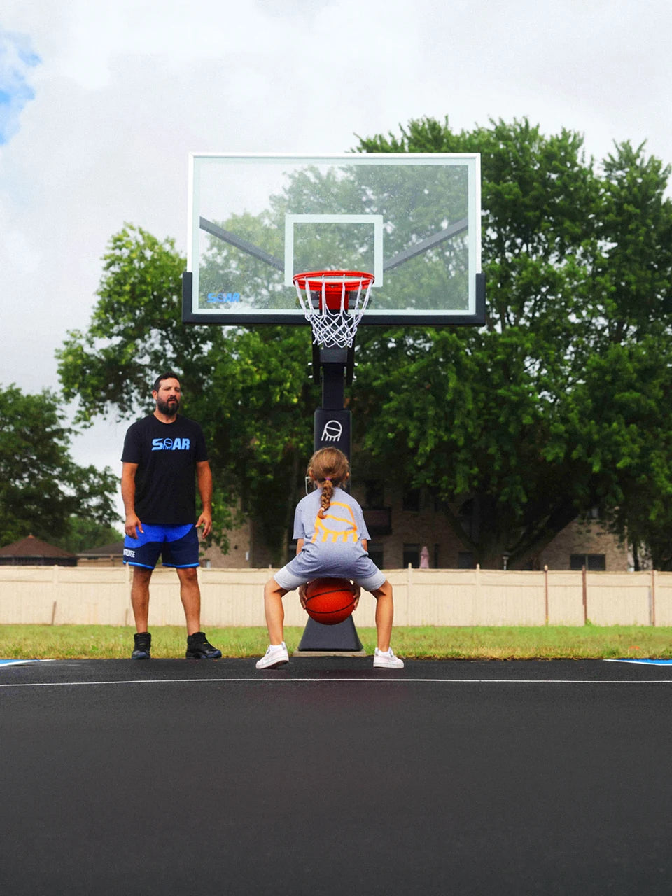 A dad and daughter spending time together beneath a SOAR basketball hoop