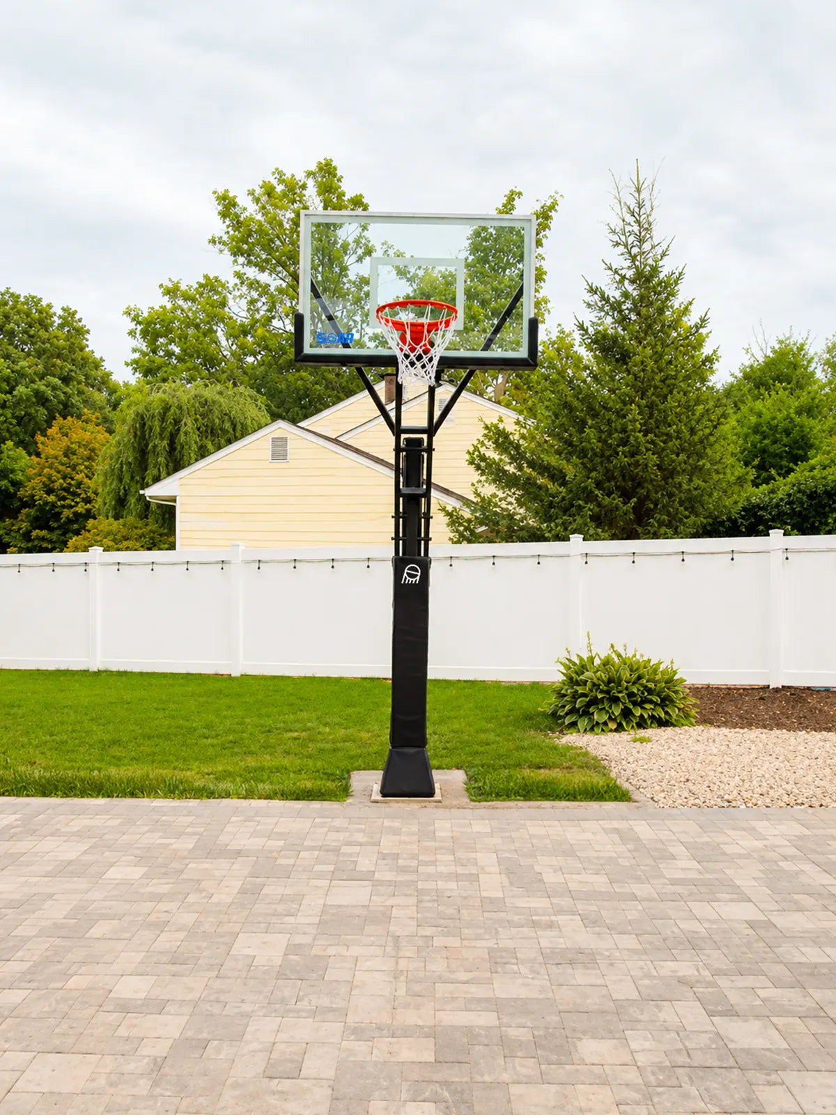 SOAR basketball hoop on a paved driveway beside a white fence