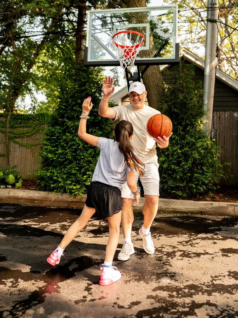 An adult and child playing basketball at a SOAR hoop