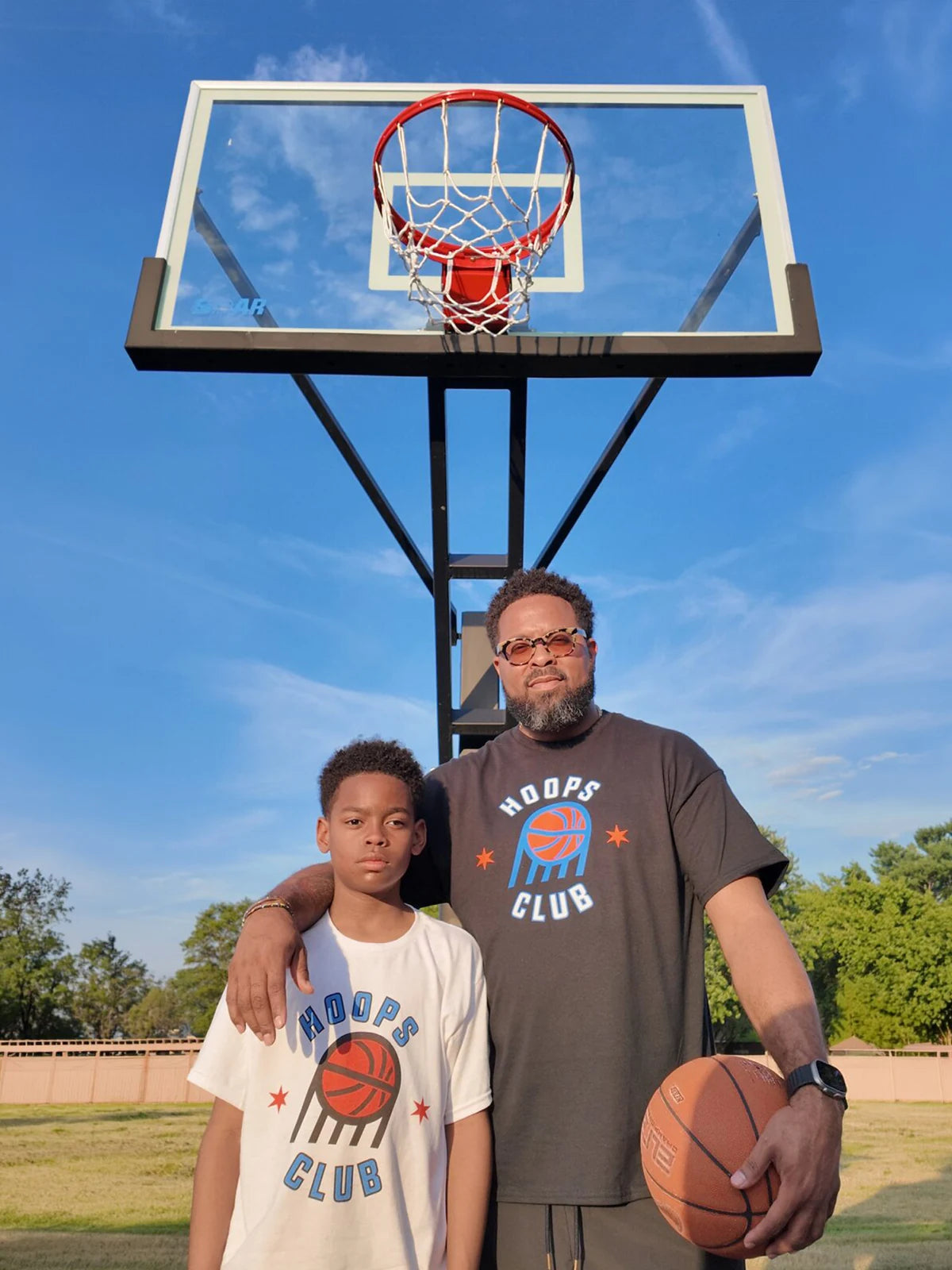 An adult and child standing together beneath a SOAR basketball hoop