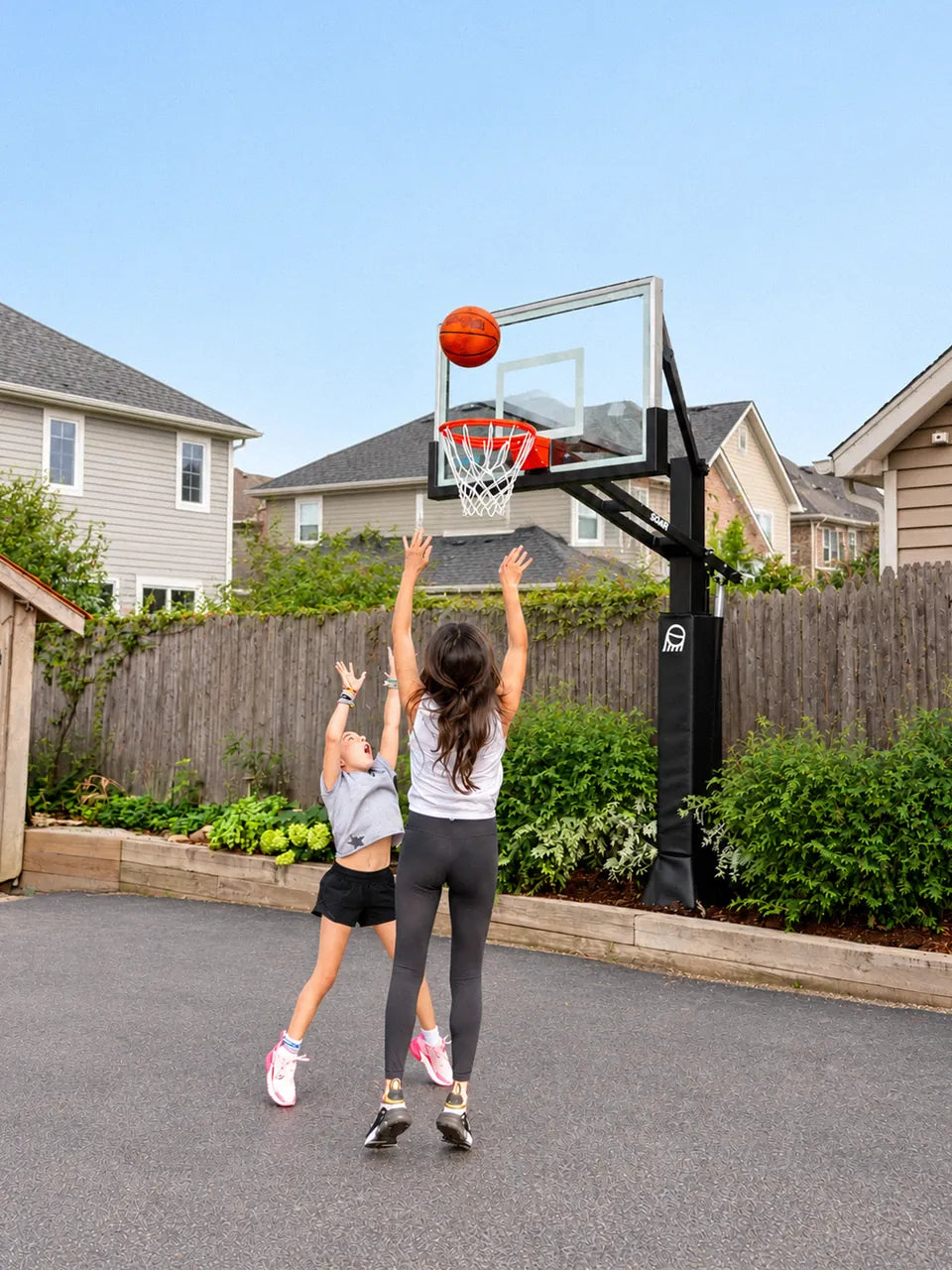 A mom and daughter shooting together at a SOAR hoop in their driveway